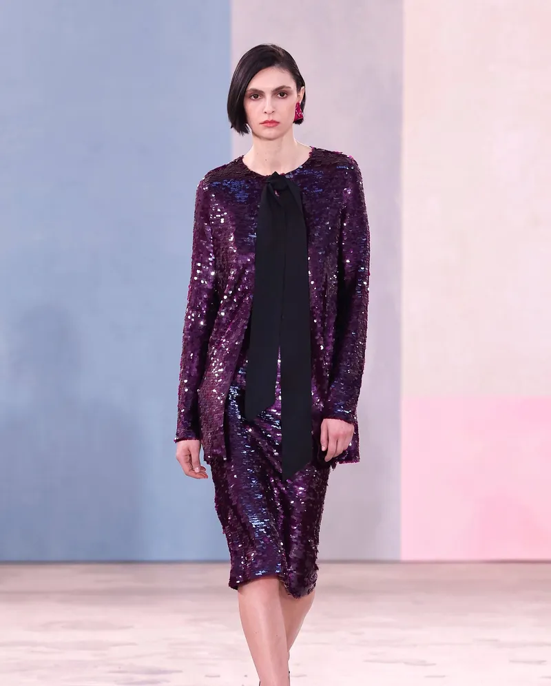 Carolina Herrera FW2026 lila paljettöverdel med svart knytrosett och matchande kjol