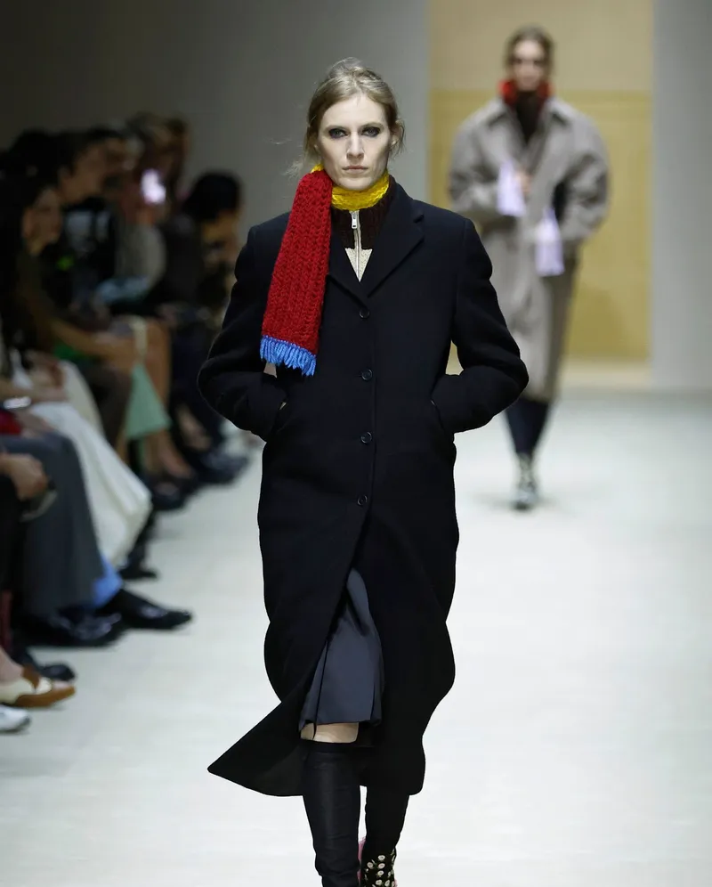 Prada FW2026 lång svart kappa med röd handstickad halsduk